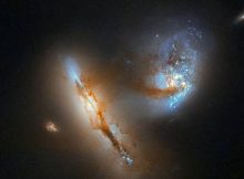 The pair of strange, luminescent creatures at play in this image are actually galaxies — realms of millions upon millions of stars.