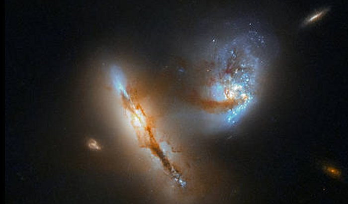 The pair of strange, luminescent creatures at play in this image are actually galaxies — realms of millions upon millions of stars.