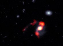 SDSS J1448+1010 is a newly-dormant massive galaxy that was born when the Universe was at roughly half of its current age, and is nearing the completion of a merger with another galaxy. During the course of this merger, the force of gravity flung what amounts to nearly half of the system’s star-forming gas away from the galaxy, leaving it unable to form new stars. This composite image combines blue/white data from the Hubble Space Telescope (HST) and red/orange data from the Atacama Large Millimeter/submillimeter Array (ALMA) to show the post-merger distribution of gas and stars from the now-dormant galaxy into streams of material known as tidal tails. Credit: ALMA (ESO/NAOJ/NRAO), J. Spilker et al (Texas A&M), S. Dagnello (NRAO/AUI/NSF)